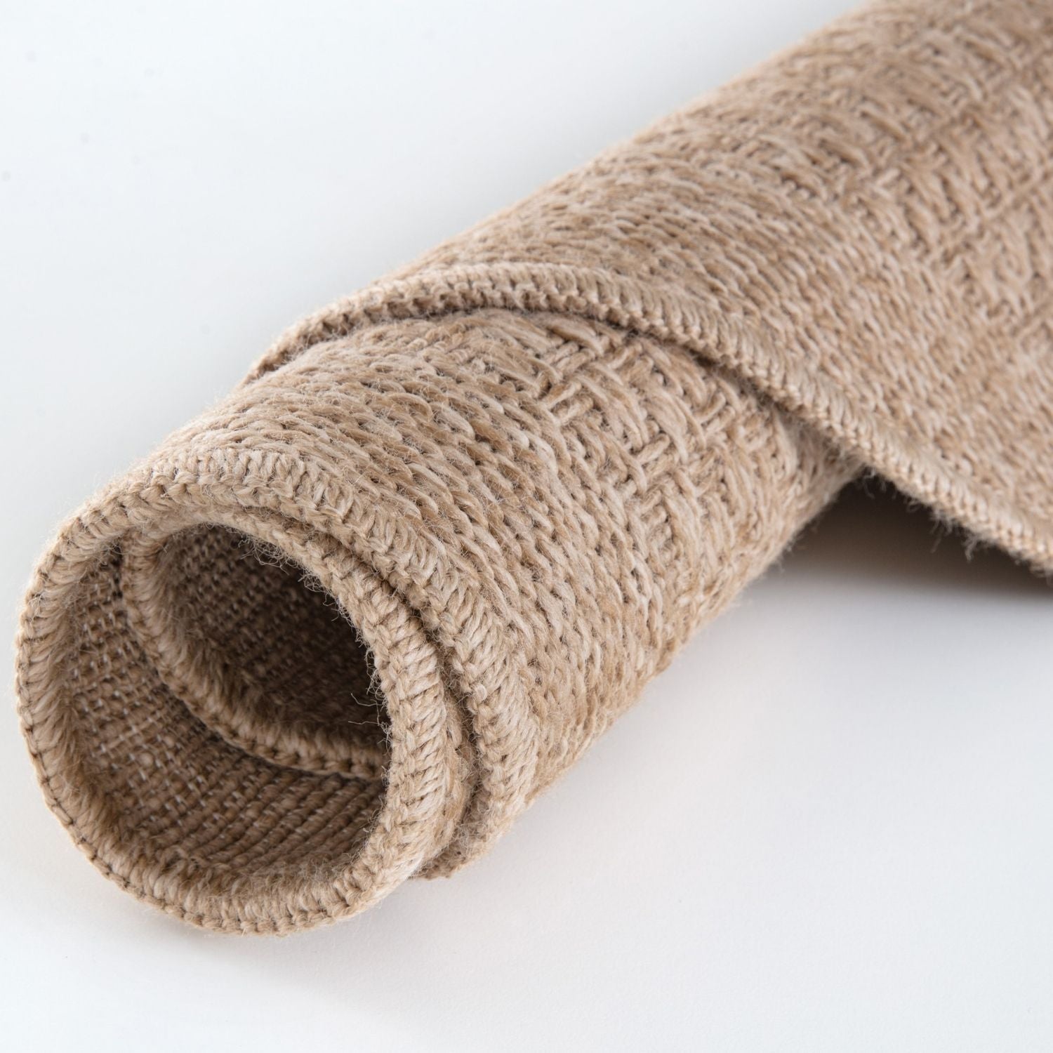 A rolled beige burlap nature outdoor rug with a coarse woven texture perfect as an outdoor rug neutral option