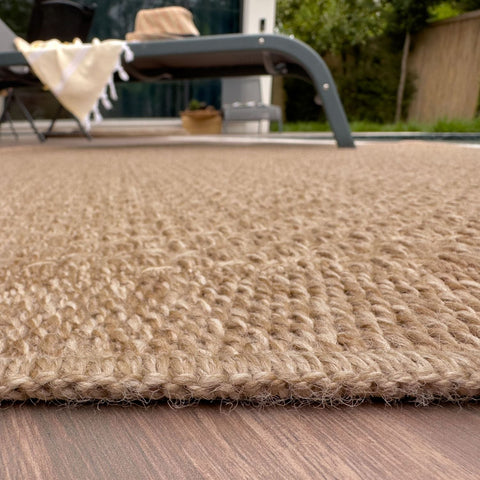 Beige woven jute nature outdoor rug with textured braided surface and frayed edges perfect as outdoor rug neutral