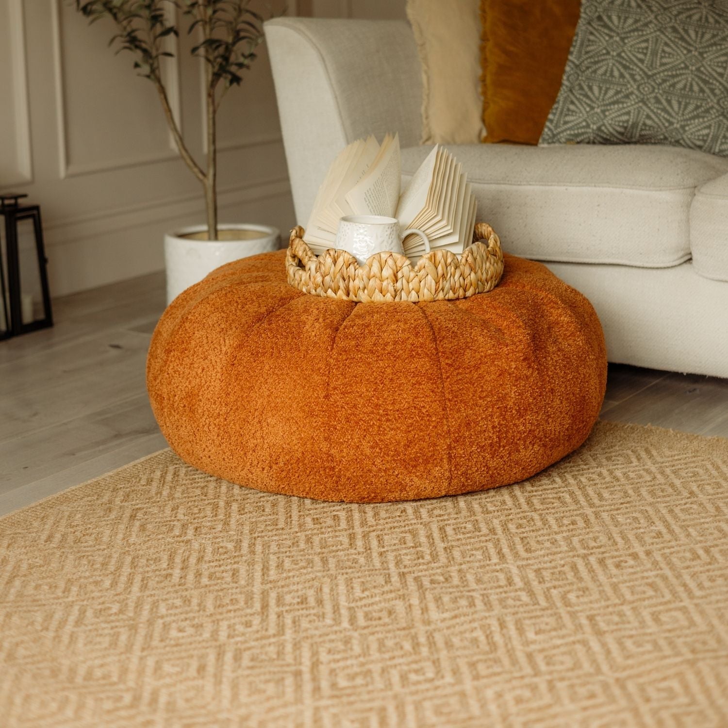 Orange plush round floor pouf shown with nature outdoor rug neutral perfect for cozy outdoor spaces