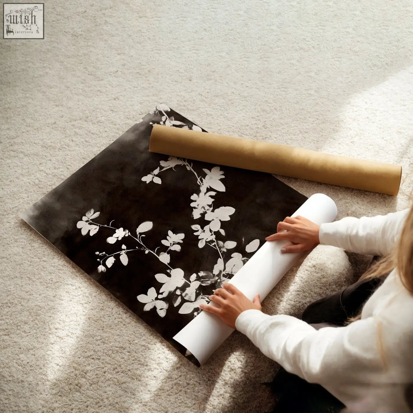 A roll of black and white dark brown-black nature painting art prints with delicate leaf patterns on carpeted floor