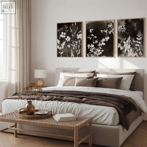 Set of 3 dark brown-black nature painting art prints with wildflower and leaf designs in thin wooden frames above bed