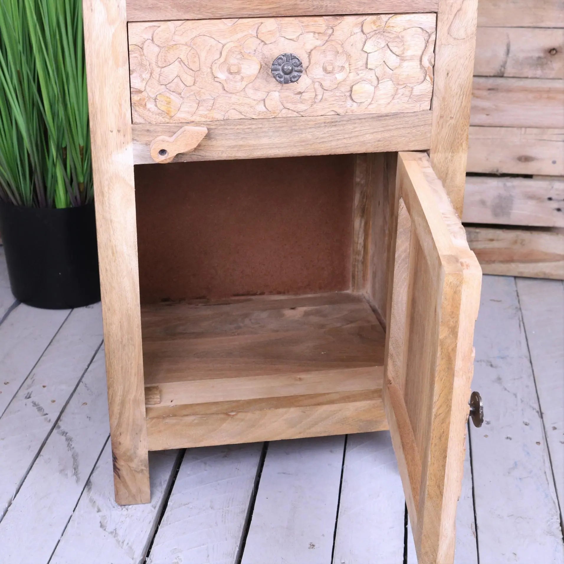 Light-colored mango wood bedside cabinet with hand carved floral patterns and decorative metal knob on drawer front