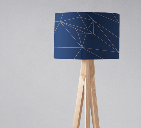 Navy blue table lamp with geometric gold line pattern on lampshade and light wood tripod base