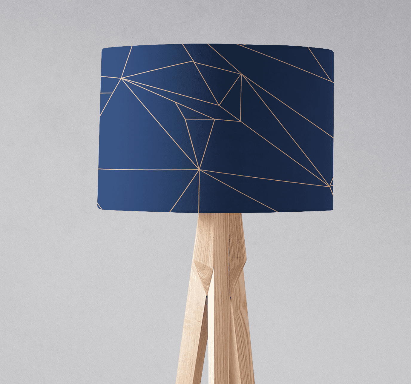 Navy blue table lamp with gold geometric line pattern on a light wood tripod base perfect for stylish decor