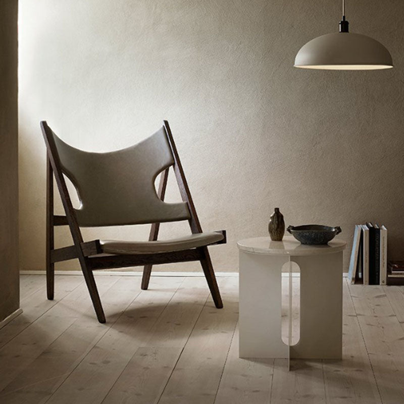 A sleek nerissa nordic side table next to a minimalist wooden chair with light gray upholstered seat and backrest