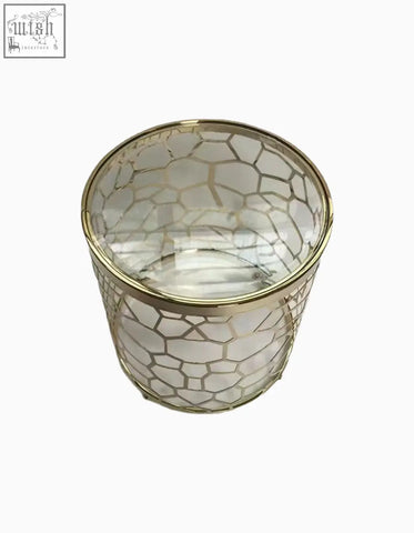 Clear glass candle holder with gold geometric lattice and metallic rim on nested glass side table with sintered stone top