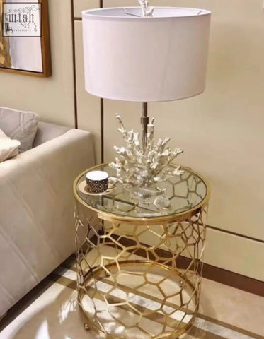 Nested glass side table with gold-toned honeycomb metal frame and clear top with ornate silver coral lamp base
