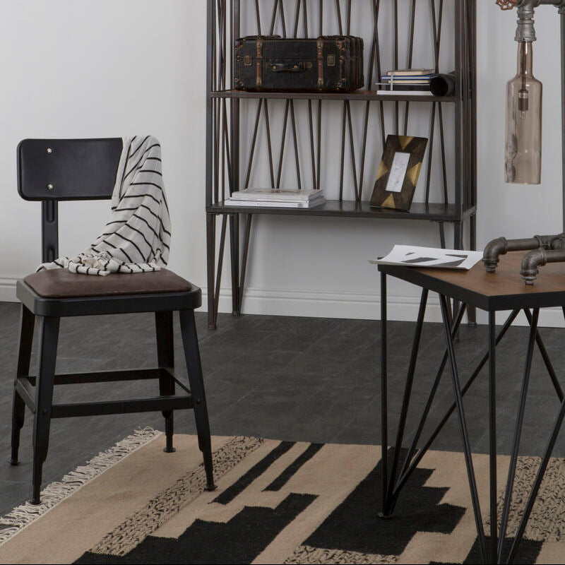 Black metal bar stool with brown leather seat and striped throw back near foundry square distressed black side table