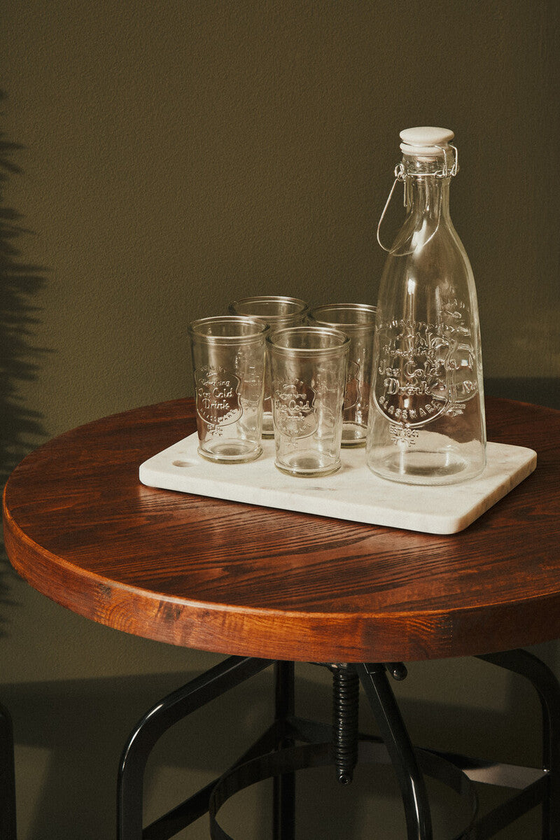 Clear glass carafe with white cork stopper and glasses on marble tray on new foundry walnut and black metal bar table