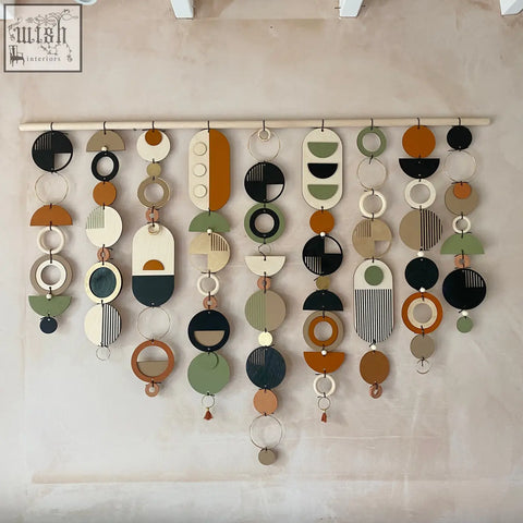 Modern wall art featuring hanging wooden discs and rings in earthy tones for trendy home decor centerpiece