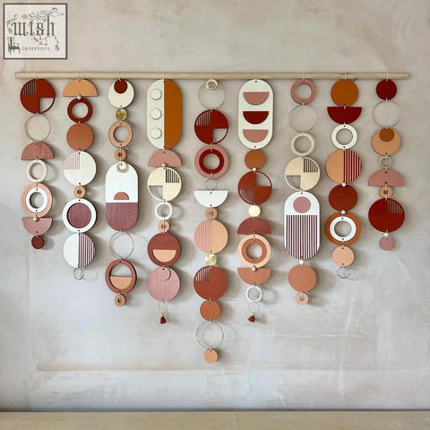 A modern wall art with layered wooden discs in warm terracotta cream and white featuring minimalist patterns