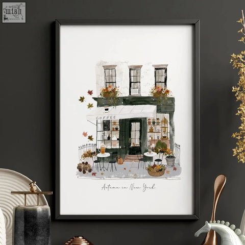 A framed watercolor travel wall art of a cozy new york coffee shop with autumn leaves in a black frame