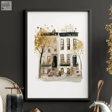 A framed watercolor travel wall art of a white townhouse with black trim and golden autumn trees in new york