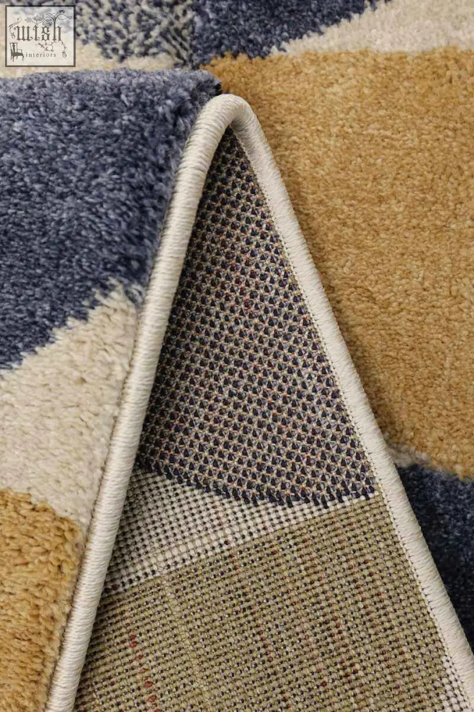 A plush newport geometric rug with soft blue beige and tan sections and a white stitched edge design
