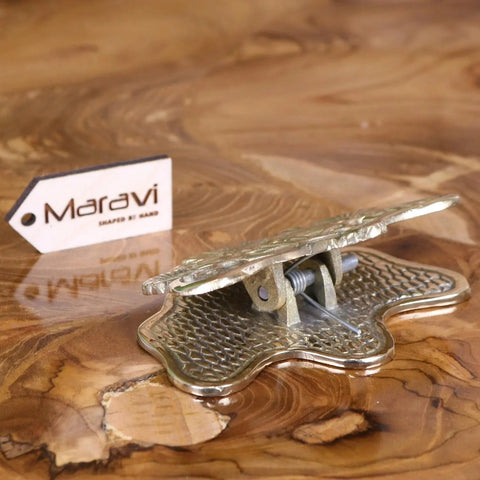 A brass-colored ornate metal clip with honeycomb base and leaf design perfect for luxury desk accessories