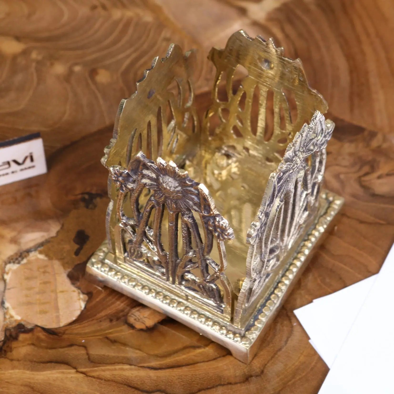 Silver and gold-toned metal napkin holder with intricate floral cutout design perfect for luxury desk accessories