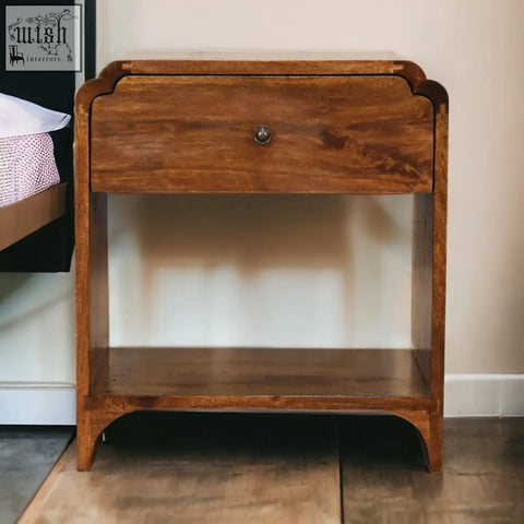 A warm-toned newton bedside table made of chestnut mango wood with a single drawer and round metal knob