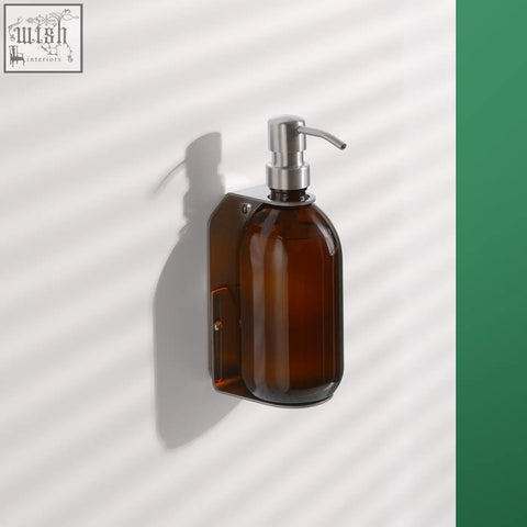 Brown amber glass wall-mounted soap dispenser with a sleek stainless steel pump and matching nickel bracket