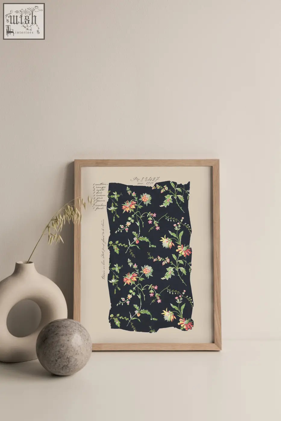 A framed botanical print with midnight blooms vintage pink and green flowers on dark navy fabric in light wood frame
