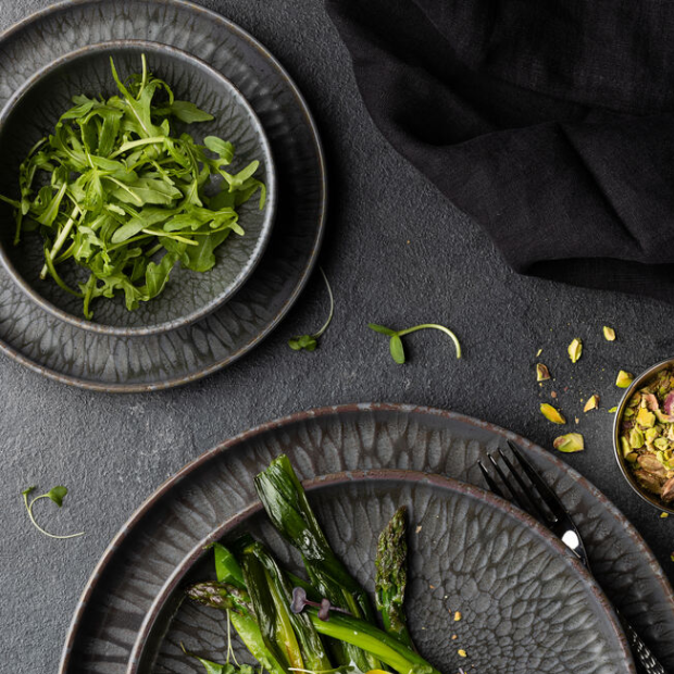 Dark gray textured nocturne bowl 6.25 inch ceramic plates with hammered finish holding arugula and grilled asparagus