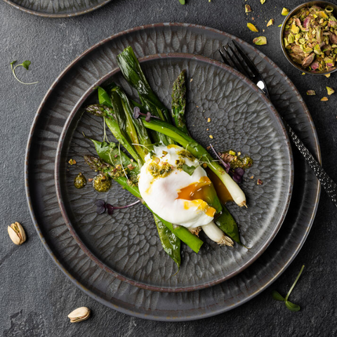 Dark gray textured ceramic nocturne coupe plate 7 inch with subtle crackled finish holding poached egg and asparagus
