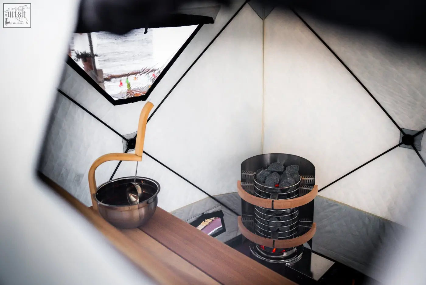 A sleek charcoal burner with wooden accents inside the r14s second tent of the noir xxl signature sauna safety pack