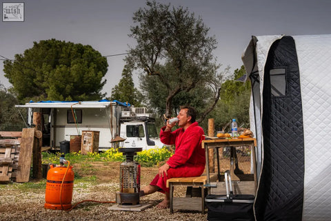 Man in red robe sitting outdoors inside noir xxl signature finssteam flagship two-tent sauna suite r14s safety pack