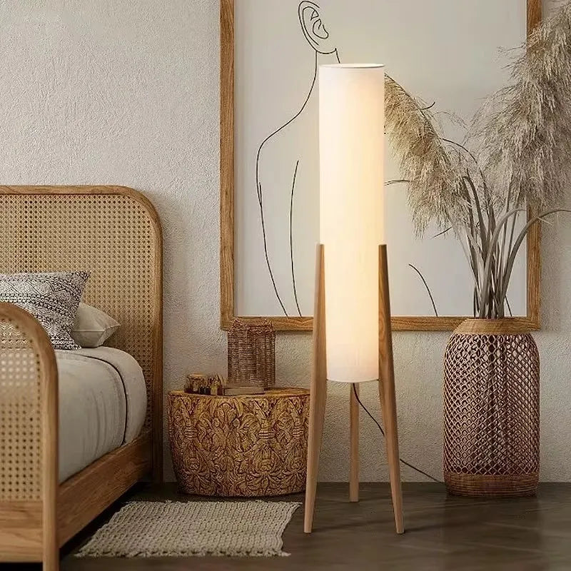 A tall nordi light floor lamp with a frosted glass cylindrical shade and three light wood legs