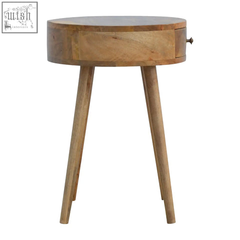 A nordic circular shaped bedside table made of oak mango wood with a round top, single drawer, and tapered legs