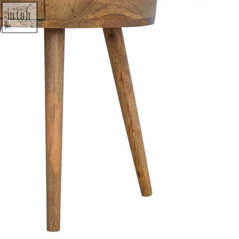 A nordic circular shaped bedside table made of warm oak mango wood with slender tapered legs and natural finish