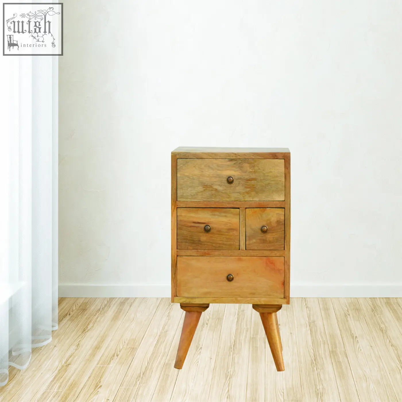 A rustic bedside table with three drawers and tapered legs made of solid mango wood in warm oak finish