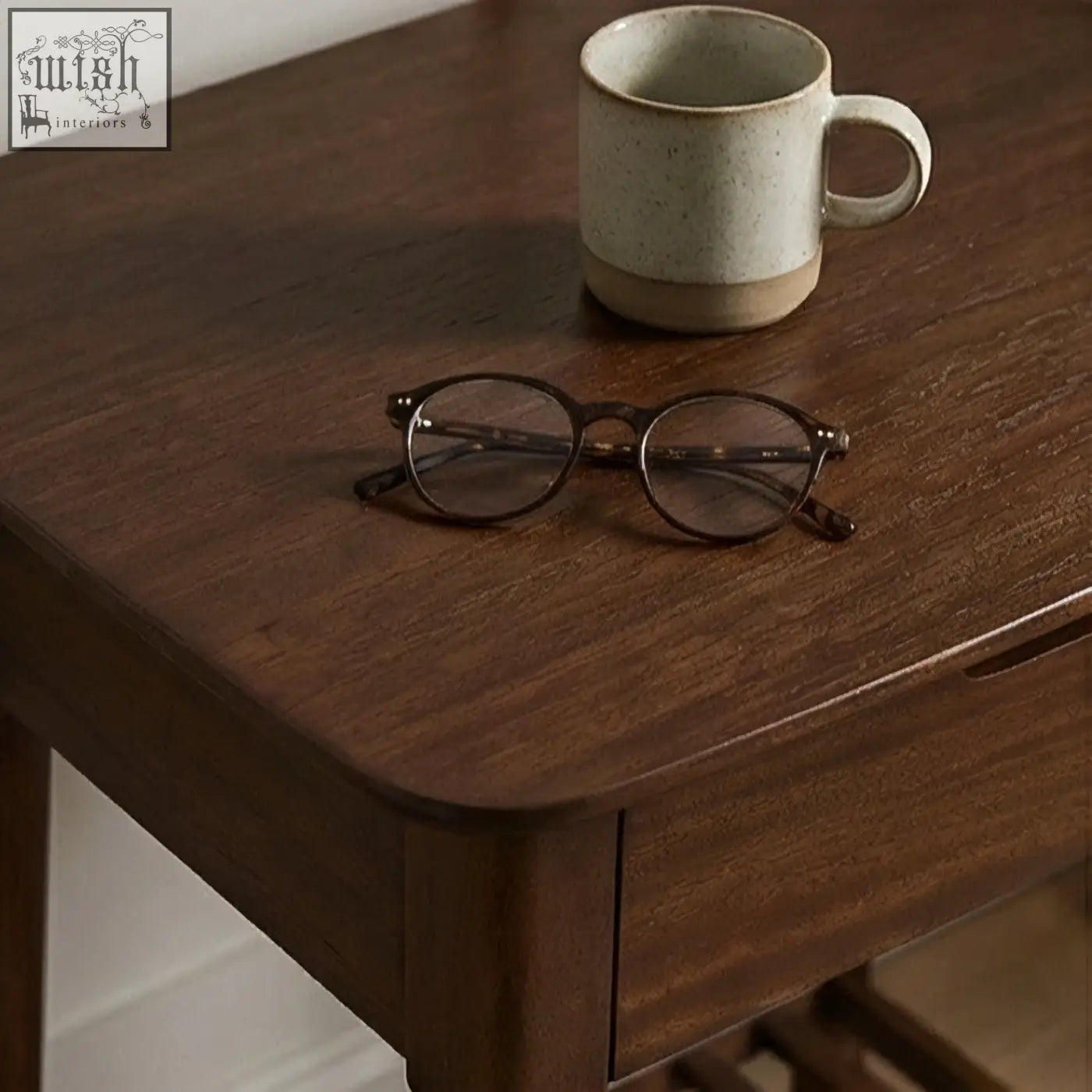 A pair of tortoiseshell reading glasses on a dark wood norway walnut bedside table with solid white cedar accents