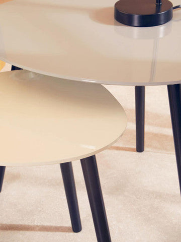 Cream-colored glass-top triangular nesting tables with sleek black legs from the nostra set of 2