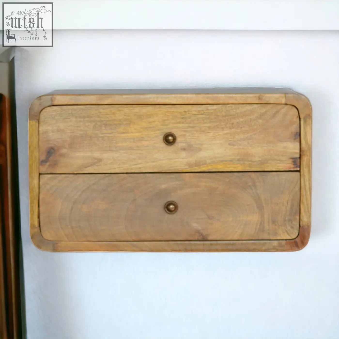 A rustic oak-ish drawer floating bedside table with two wall-mounted drawers in natural wood and brass knobs