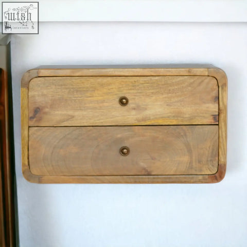 A rustic oak-ish drawer floating bedside table with two wall-mounted drawers in natural wood and brass knobs