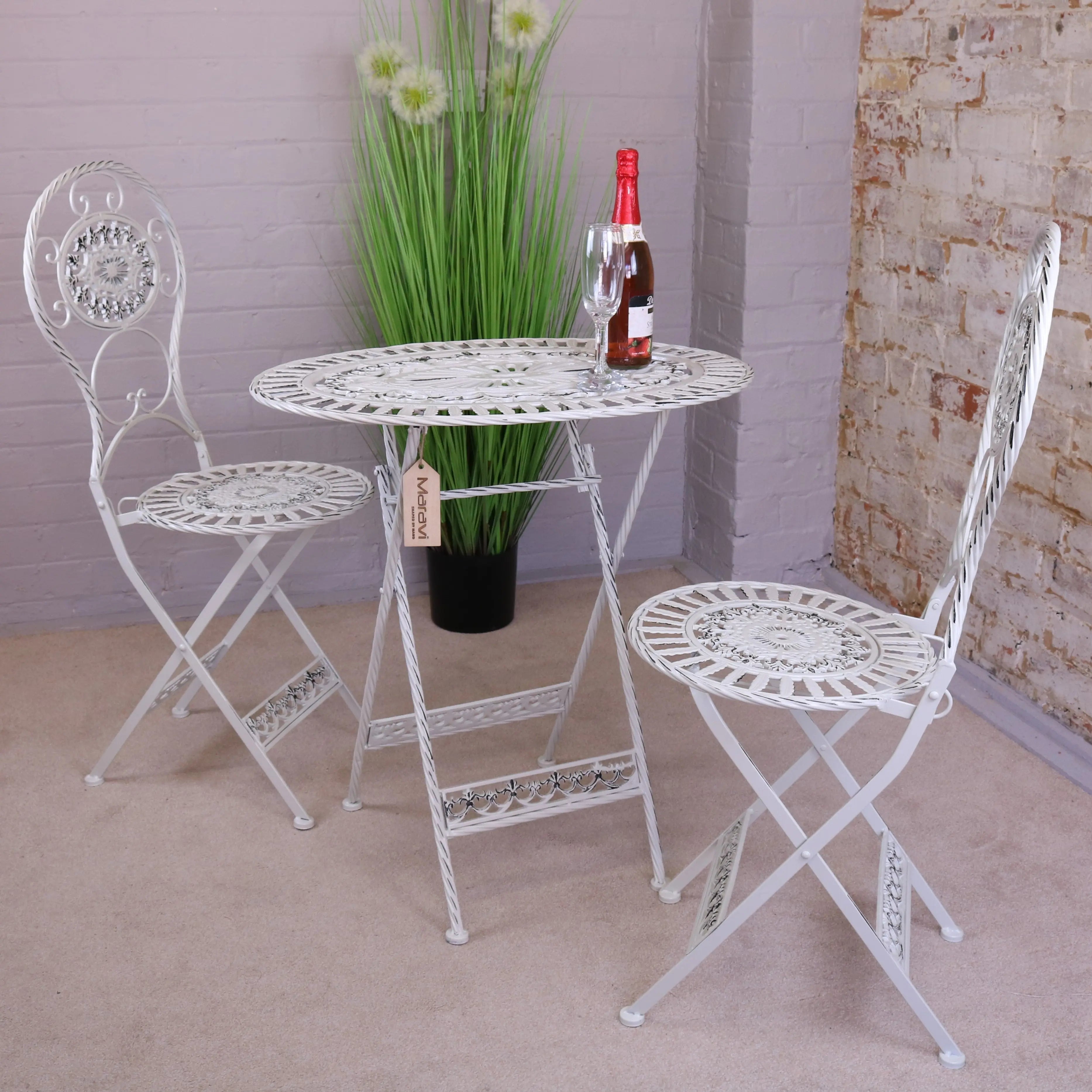 White wrought iron oval garden table with ornate scrollwork and lace like circular pattern for outdoor use