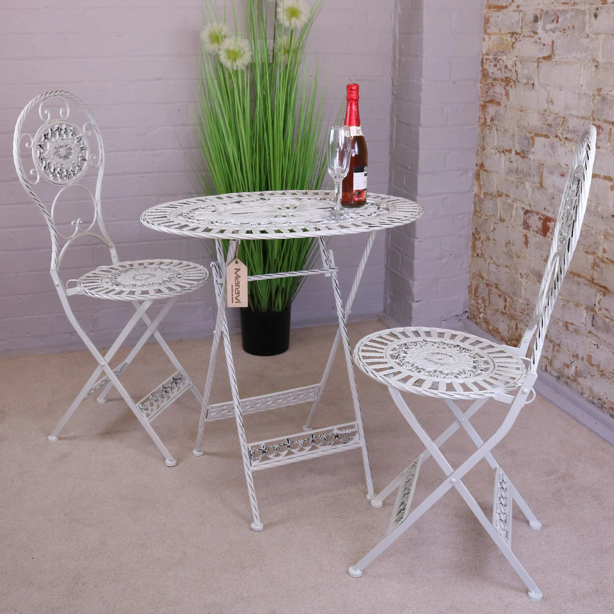 White wrought iron oval garden table with ornate scrollwork and lace like circular pattern for outdoor use