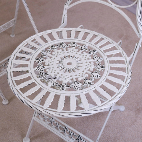 White wrought iron patio chair with intricate floral scrollwork from odal 3 piece oval garden table set