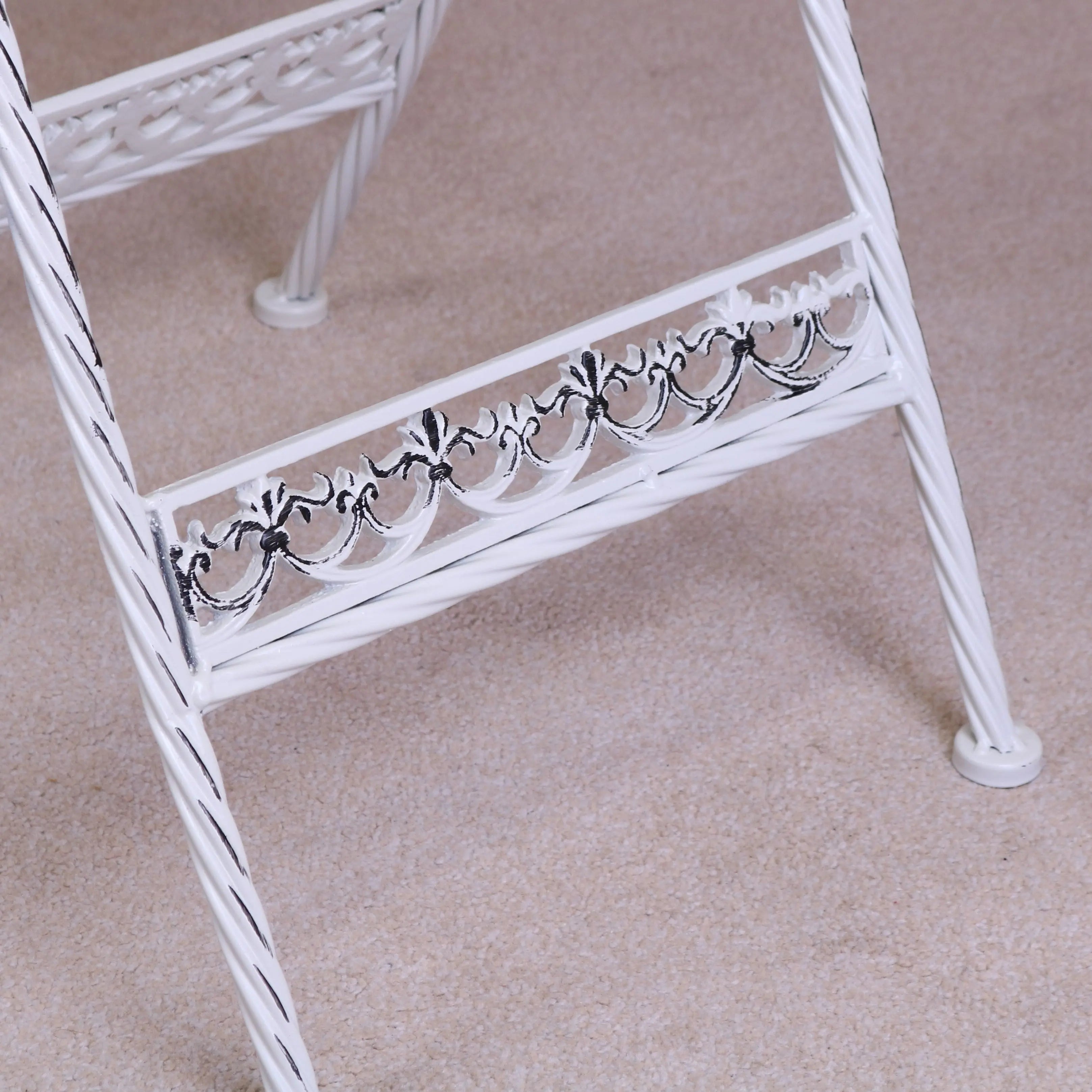 White wrought iron plant stand with twisted legs and black scrollwork fits perfectly with oval garden table set