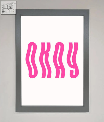 A framed poster with bold wavy pink okay lettering on a white background for stylish wall decor