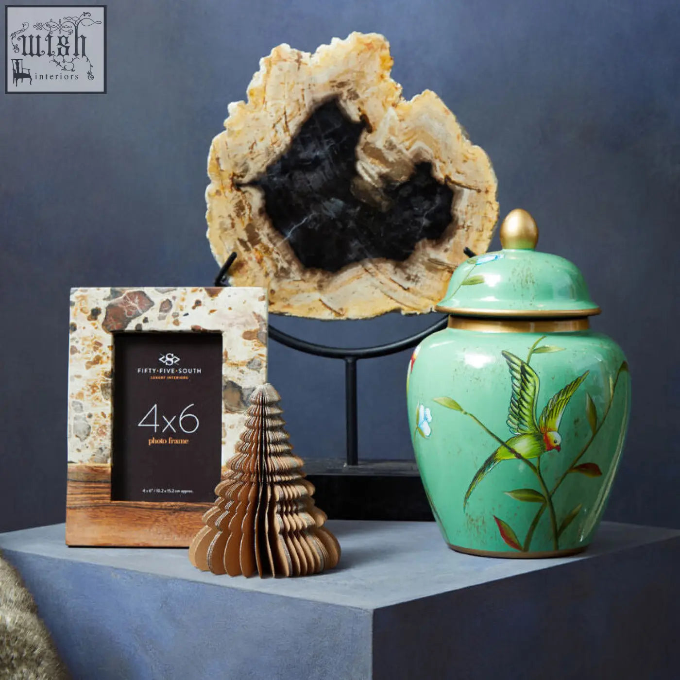 Turquoise ceramic jar with gold lid and hand-painted green bird design next to olena marble and acacia large photo frame