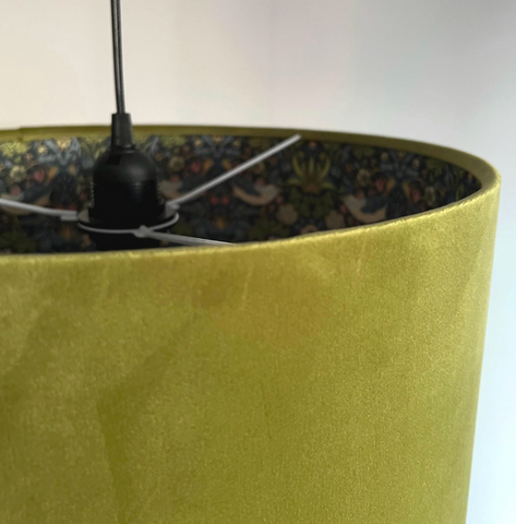 A mustard-yellow velvet lampshade showing the dark patterned interior of a double sided olive green velvet ceiling light shade