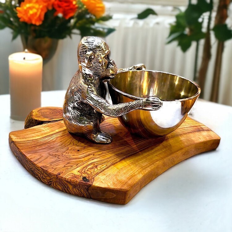 Silver monkey figurine holding a gold metal bowl on a rustic olive wood base perfect for serving snacks