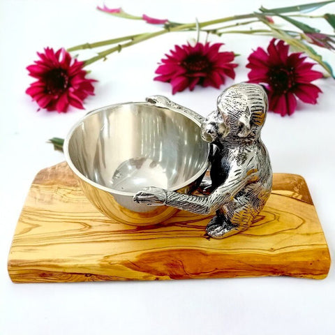 Silver monkey-shaped serving bowl with detailed fur and olive wood base holding a round reflective interior