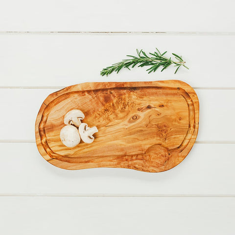 A rustic oval olive wood carving board with natural grain knots and a groove for easy cutting tasks