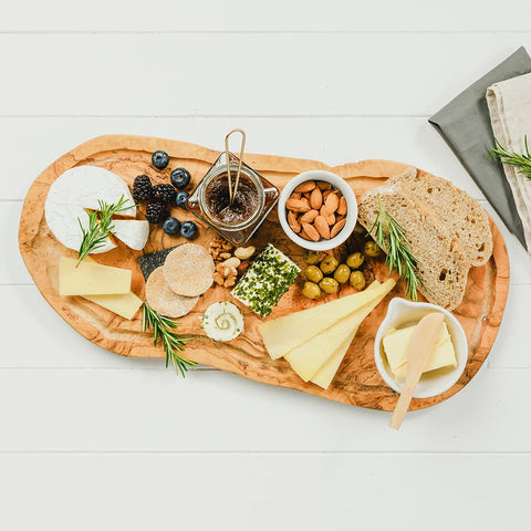 A rustic olive wood carving board with groove featuring natural organic grain and irregular edges for serving cheese