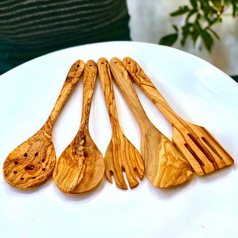 Set of five handcrafted olive wood kitchen utensils with natural grain and warm golden-brown tones for cooking
