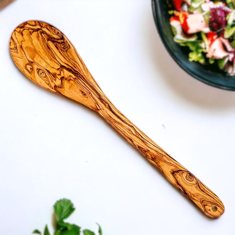 A beautifully crafted olive wood cooking spoon with warm golden-brown finish and swirling grain patterns perfect for serving