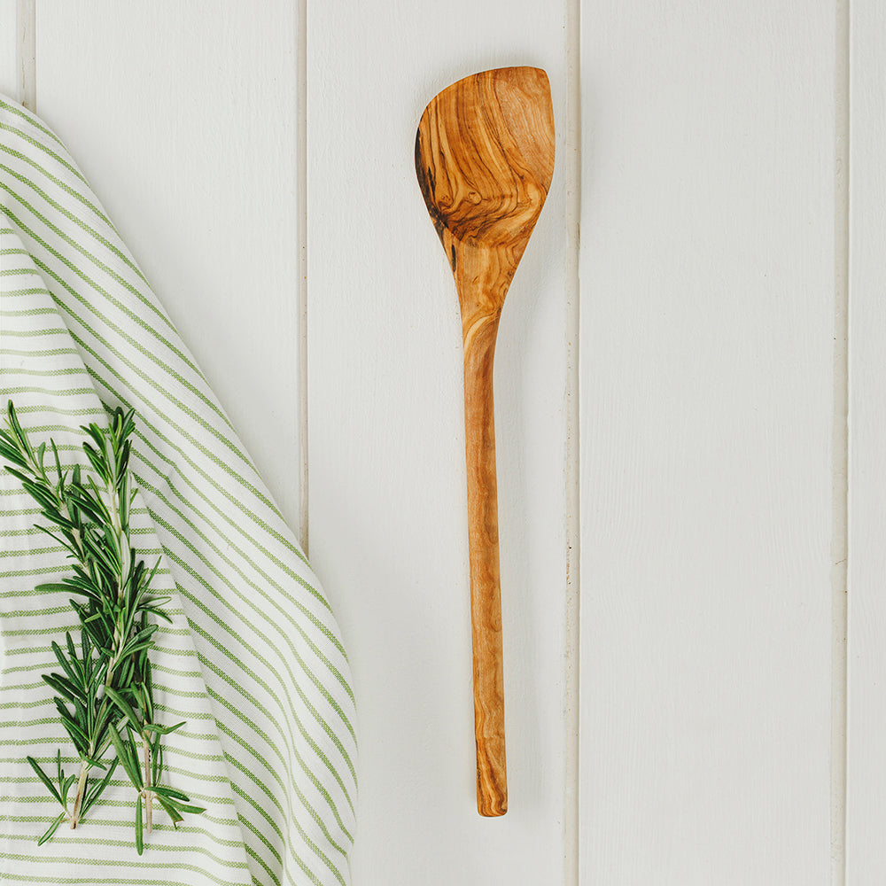 A rustic olive wood corner spoon with a smooth natural finish and unique swirling grain pattern