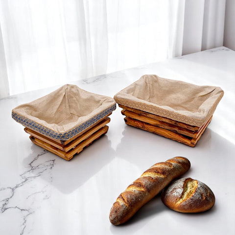 Two olive wood rectangular bread baskets with beige linen interiors and blue patterned trim for serving bread